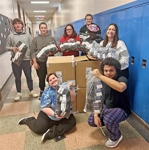 Students post with socks to donate